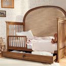 Maxi Cosi Quiet Luxury 6-in-1 Convertible Crib featuring a wooden frame, plush bedding, and a storage drawer below.