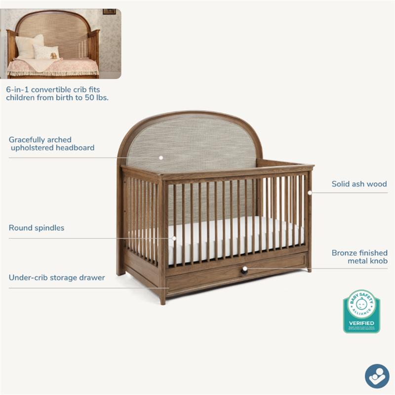 Maxi Cosi Quiet Luxury 6-in-1 Convertible Crib with upholstered headboard, round spindles, and under-crib storage drawer.