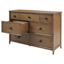 Maxi Cosi Quiet Luxury 7-drawer dresser in a warm wood finish, featuring six closed drawers and one partially opened drawer.