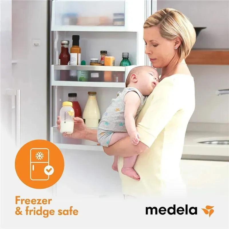 Breast milk collection and storage bottle by Medela, held by a woman with a baby in her arms, standing by an open refrigerator. Freezer and fridge safe label visible.