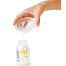 Medela milk collection shells pouring breast milk into a clear measuring bottle, showcasing the product in use.