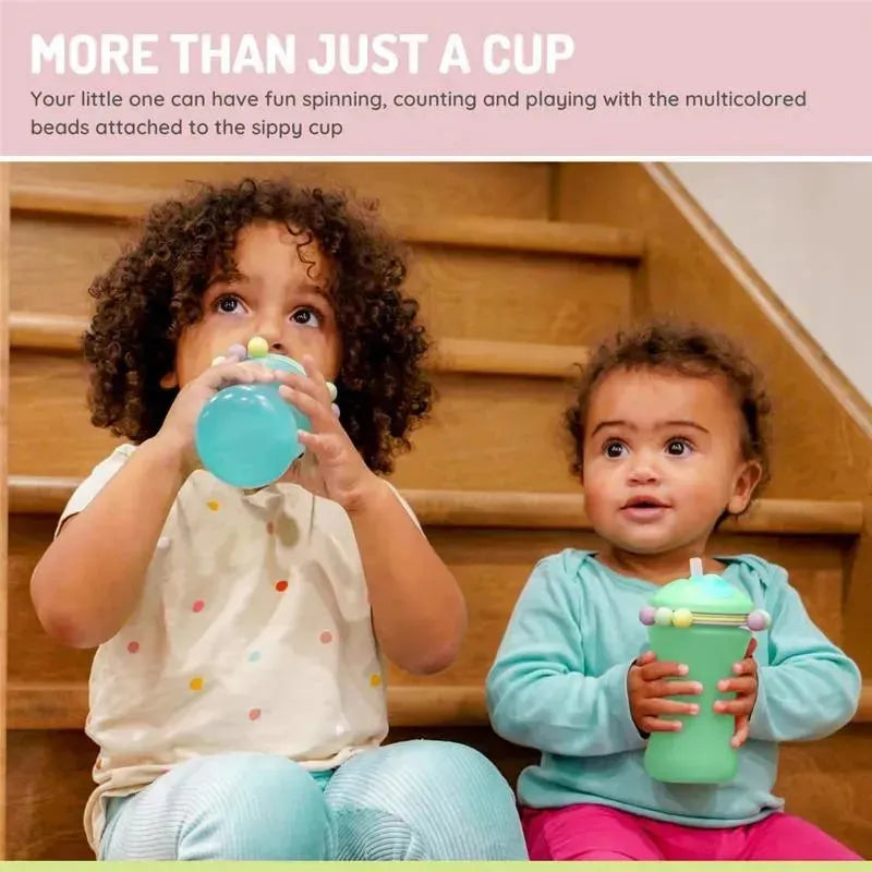 Two children sit on stairs holding Melii sippy cups, one mint green with beads, and one light blue.