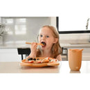 Child with light brown hair eating from a bear-themed bamboo meal set, featuring fruits on a plate and a soft cup nearby.
