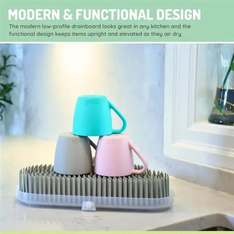 Countertop baby bottle drying rack with three colorful cups (grey, teal, pink) standing on upright drying prongs.