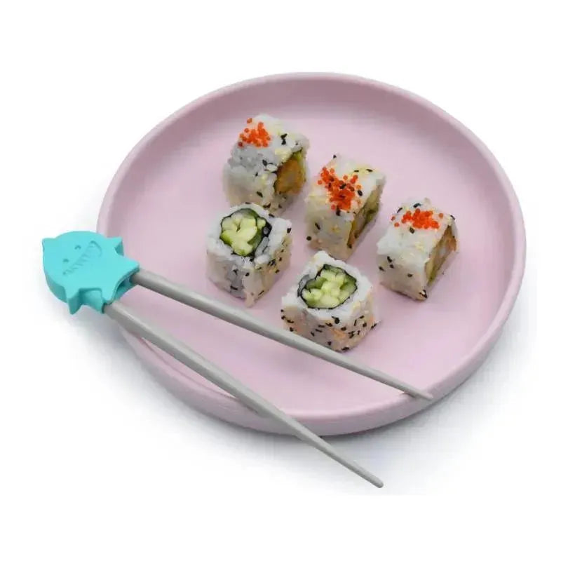 Chopsticks designed as a shark, next to sushi rolls on a pink plate, highlighting the playful training aspect of the product.