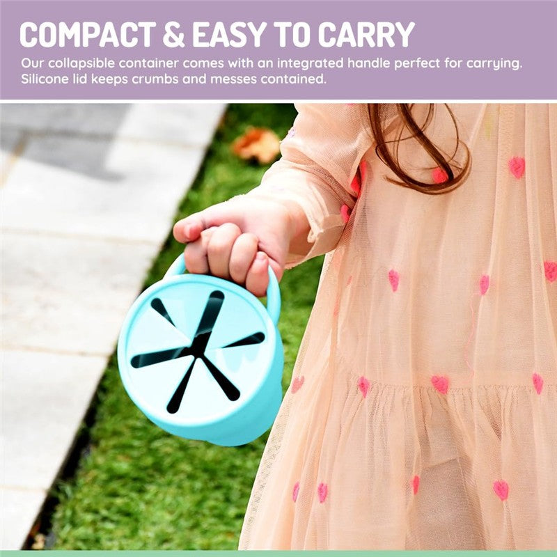 Collapsible blue silicone container with a handle, being held by a child, designed to contain crumbs and messes.