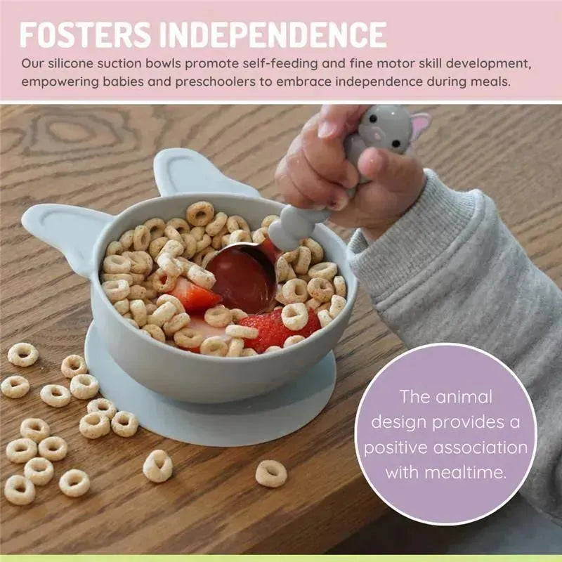 Silicone suction bowl with ears, filled with cereal and strawberries, being used by a child with a spoon.