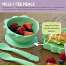 Silicone suction bowl in Dino Green with mixed berries, secure suction base, and two matching spoons for toddlers.