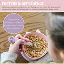Silicone suction bowl in unicorn pink with a child using a spoon to self-feed cereal, promoting independence at mealtime.