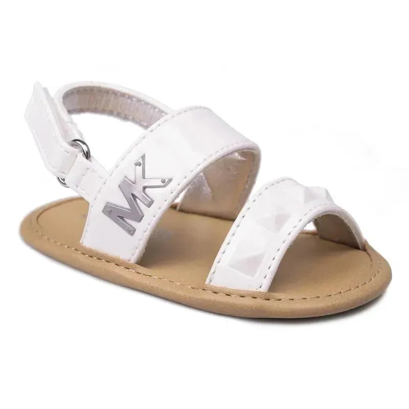 White patent baby sandals by Michael Kors featuring a closed toe design, adjustable strap, and silver MK logo.