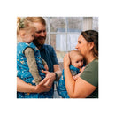 Parents hold two babies wearing bright blue Finding Nemo sleep bags while smiling in a cozy indoor setting.