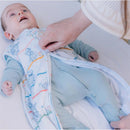 Baby in a Disney Pixar Toy Story sleep bag, being zipped up by a caregiver, smiling. The sleep bag features colorful character illustrations.