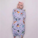 Swaddled baby in a pastel blanket featuring Disney Princesses, including Snow White and Cinderella, with a pink headband.