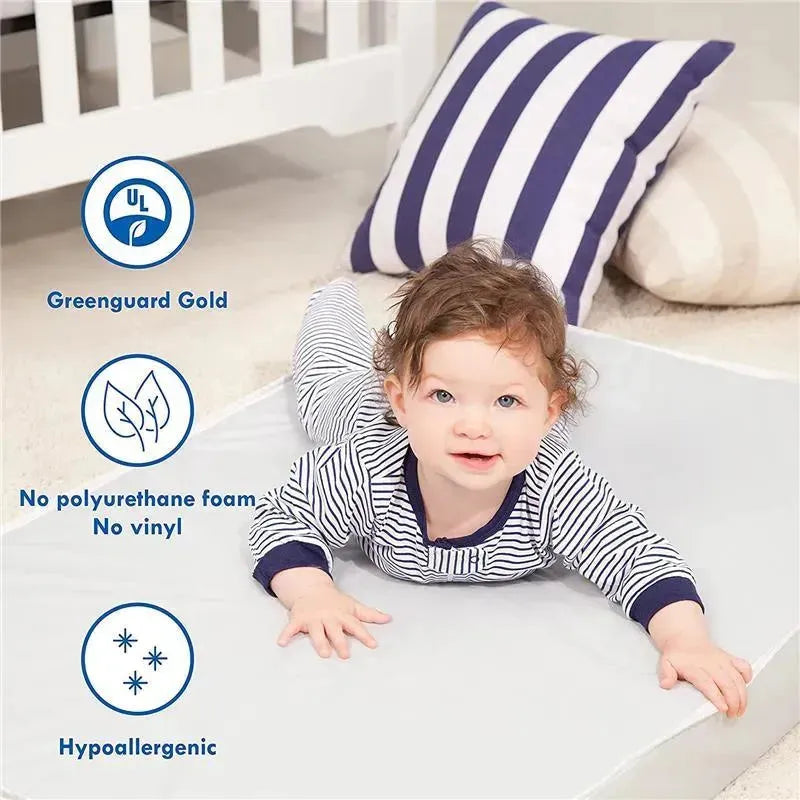 Baby lying on a soft surface, wearing a striped outfit, with a crib and pillows in the background; features eco-friendly mattress highlights.