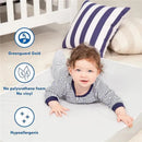 Baby lying on a soft surface, wearing a striped outfit, with a crib and pillows in the background; features eco-friendly mattress highlights.