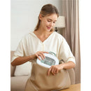 A woman inserts the Momcozy All-in-1 Core Baby Kit into a large beige handbag, smiling while handling the product.