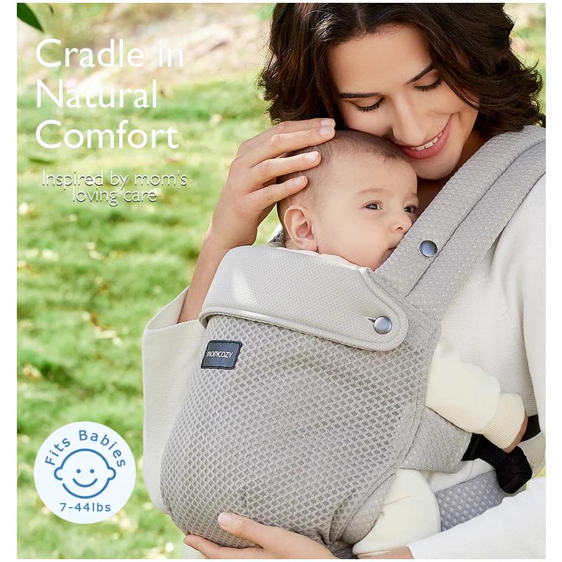 Momcozy baby carrier in mesh grey, comfortably holds a smiling infant while a woman gently cradles them outdoors.