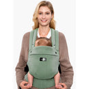 Momcozy baby carrier in sage green, worn by a smiling woman, holding a baby securely in front.