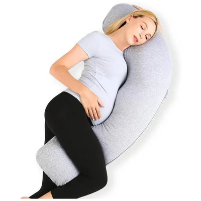 A pregnant woman relaxes while using a grey J-shaped maternity body pillow for support.