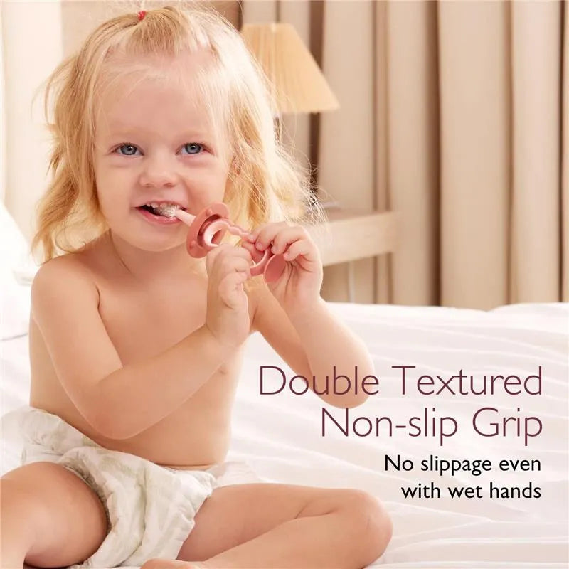 Child smiling while holding a toothbrush with a double textured non-slip grip, promoting ease of use.