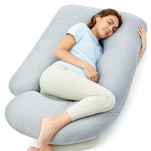 U-shaped pregnancy pillow in a light gray fabric, with a woman comfortably asleep while hugging it.