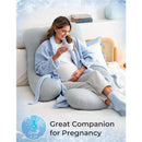 U-shaped cooling fabric pregnancy pillow supporting a smiling pregnant woman enjoying tea in a cozy setting.