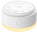 White Momcozy white noise machine with control buttons and a soft amber light at the base.