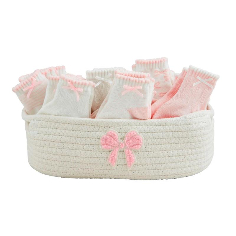 Pink baby girl socks in a white basket featuring a decorative bow, displaying various styles and patterns.