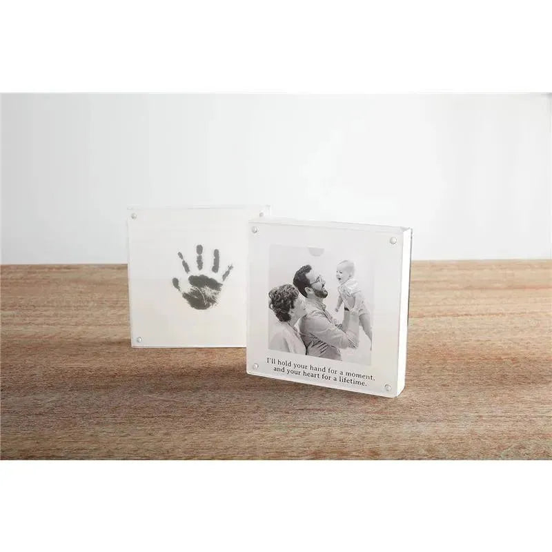 Baby handprint frame with a black handprint and a photo of a parent holding a baby, featuring sentimental text.