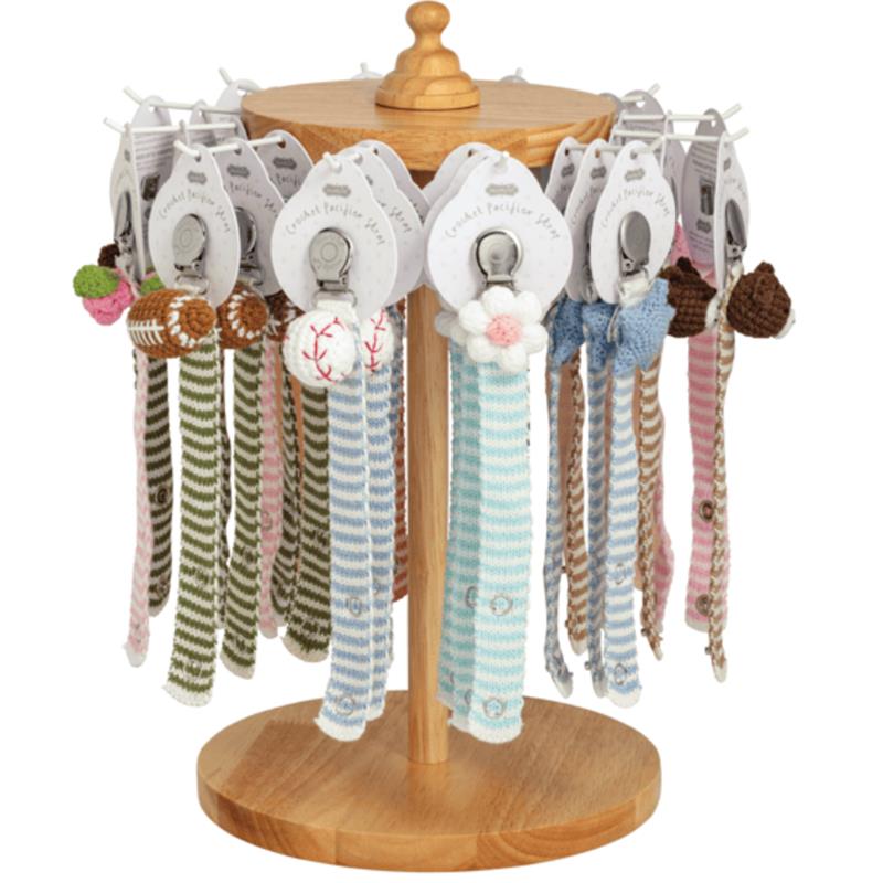 Crocheted pacifier straps in various colors and designs displayed on a wooden stand, ideal for keeping pacifiers close.