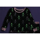 Toddler pajamas featuring a black fabric with glow-in-the-dark pink skeleton designs, including playful skeletons in various poses.
