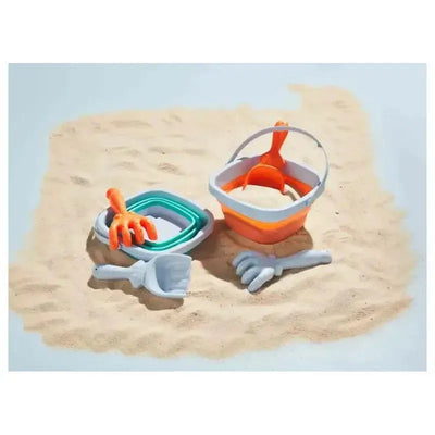 Orange collapsible bucket set with multiple nested buckets, a scoop, and a claw-shaped tool, resting on sand.