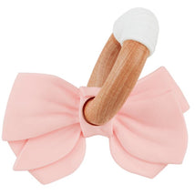 Pink silicone ring teether shaped like a bow with a wooden handle, designed for infants to chew and grasp.