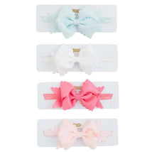 Four scalloped bow headbands in blue, white, pink, and light pink, displayed on a white card with brand label.