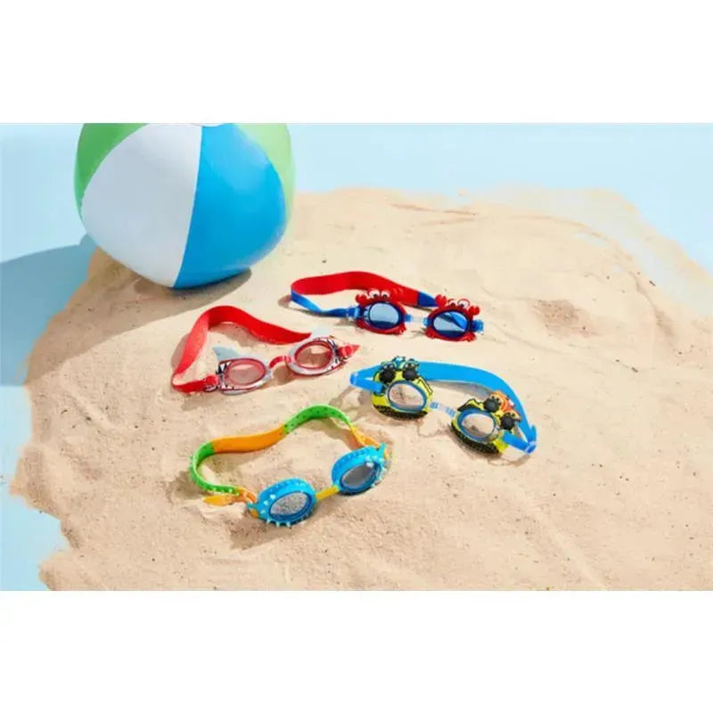 Shark Boy swim goggles in vibrant colors displayed on sand, accompanied by a beach ball.