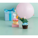 Unicorn and dinosaur birthday candles on cupcakes with pastel frosting, beside a gift box and a pink balloon.