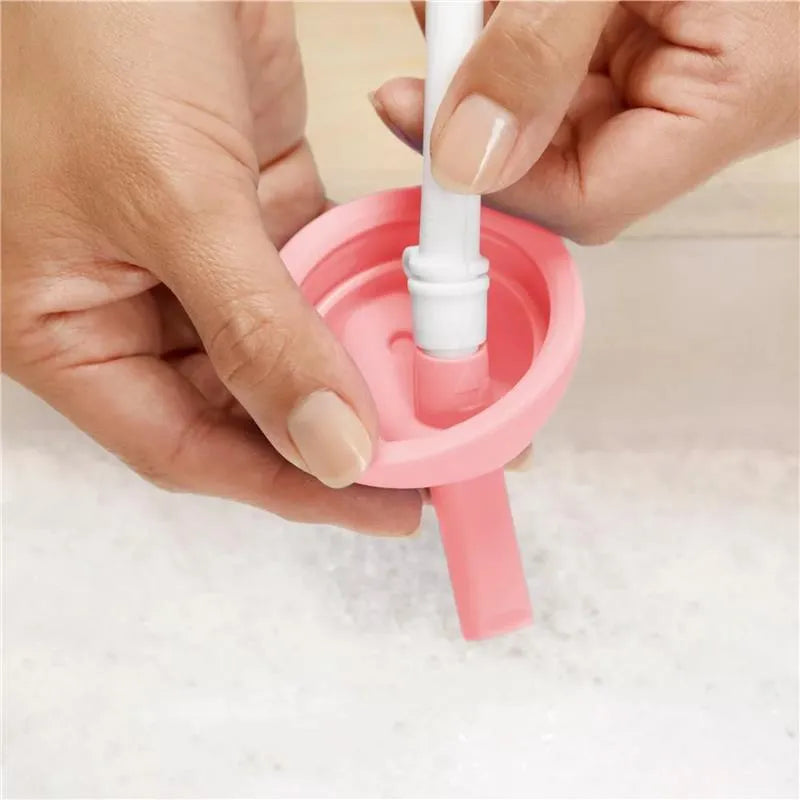 Light pink Munchkin 10oz Simple Clean Straw Cup being cleaned, with a hand holding the straw and cup lid.