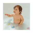A happy baby playing in a bubbly bath with colorful Munchkin floating toys in the water.