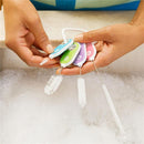 Four colorful cleaning brushes from the Munchkin set, held above a sink filled with bubbles.