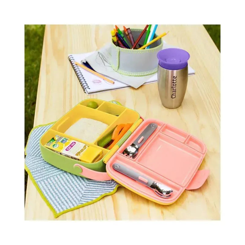 Munchkin Lunch Bento Box in yellow and pink, featuring stainless steel utensils and compartments for food, on a wooden table.
