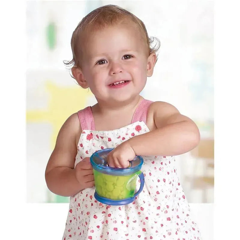 Toddler smiling while holding a Munchkin Snack Catcher filled with snacks, designed to minimize spills.