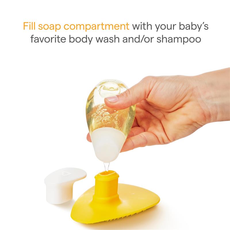 Munchkin Squeeze & Scrub silicone baby bath brush, with a hand filling the soap compartment, featuring a yellow brush and white cap.