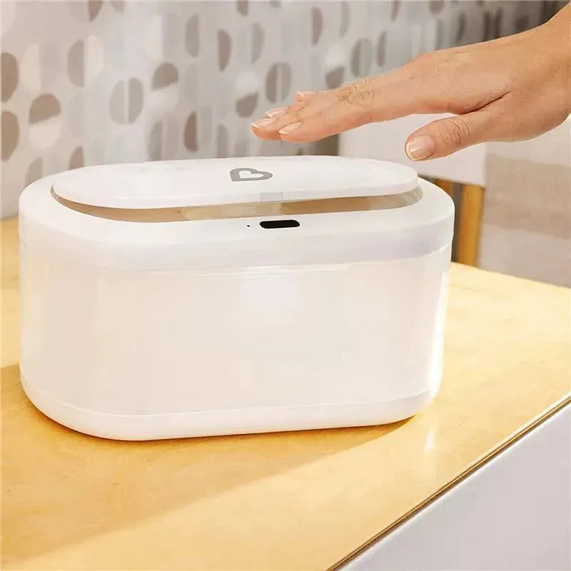 Touch-free wipe warmer by Munchkin, featuring a hand sensing area, placed on a wooden surface.