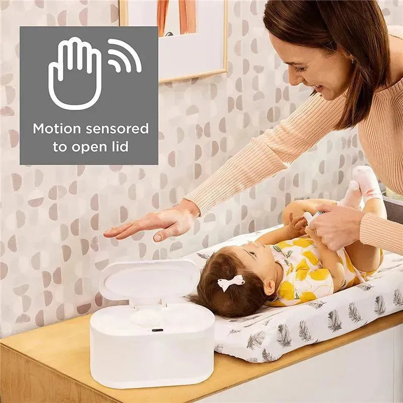 Touch-free wipe warmer with a motion sensor to open the lid, used by a caregiver changing a baby on a changing table.