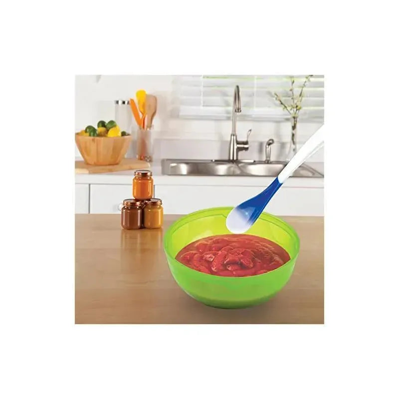 Munchkin White Hot Infant Spoons in a kitchen setting, next to a green bowl filled with red food, beside jars.