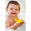 Smiling baby holding a Munchkin White Hot Safety Bath Ducky while sitting in a bathtub filled with water.