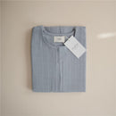 100% organic cotton muslin baby wearable blanket in Tradewinds color, folded with a tag showing the brand Mushie.