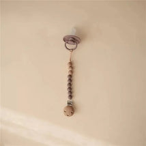 Silicone baby pacifier clip in Eva Ash color with wooden beads and clip, designed to keep pacifiers secure.