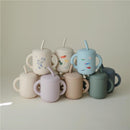 Silicone training cups in various colors with handles and straws, featuring playful designs for toddlers.