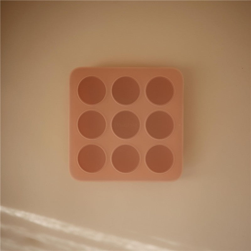Mushie Baby Food Freezer Tray in blush color, featuring nine circular compartments for freezing baby food portions.